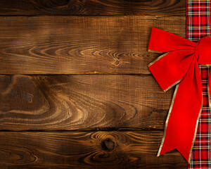  red Christmas bow on a wooden background. Christmas background, photo for a postcard or gift bag