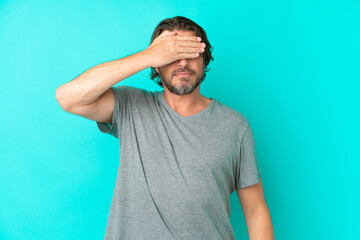 Senior dutch man isolated on blue background covering eyes by hands. Do not want to see something