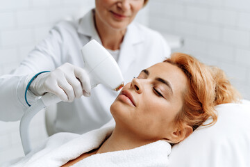 Obraz na płótnie Canvas Close up of female face getting electric facial massage by beautician. She is lying with relaxation at the special table and getting laser epilation