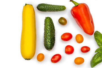 Vegetable flatlet: cucumbers, zucchini, cherry tomatoes, a sprig of basil and peppers on a white plate.