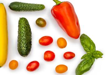 Vegetable flatlet: cucumbers, zucchini, cherry tomatoes, a sprig of basil and peppers on a white plate.