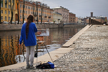In the process of creating a masterpiece. The painter on the embankment.