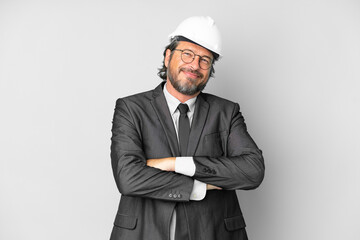 Young architect man with helmet over isolated background keeping the arms crossed in frontal...
