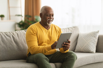Mature African American Man Using Digital Tablet Sitting At Home - Powered by Adobe