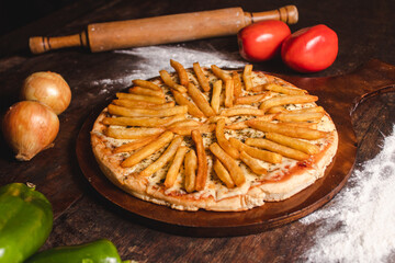 Pizza with mozzarella and fries on a wooden table.