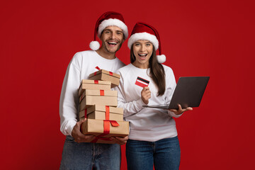 Christmas Shopping. Couple in santa hats with laptop, gifts and credit card