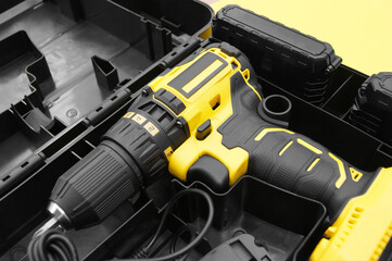 Naklejka premium The yellow-black screwdriver on a yellow background, a set of bits.