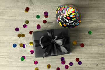Gift box, party hat and glitter on gray wooden table