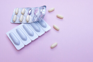 Gynecological medicines for women's health in form of suppository, capsules on pink background.