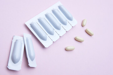 Gynecological medicines for women's health in form of suppository, capsules on pink background.