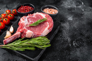 Cooking Raw Rib eye or Tomahawk beef steak with spices. Black background. Top view. Copy space