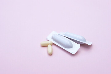 Gynecological medicines for women's health in form of suppository, capsules on pink background.