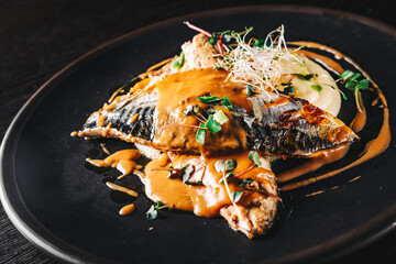 Fillet of mackerel with mashed potatoes and celery on dark background
