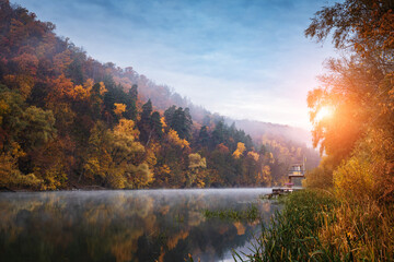 Autumn forest on a mountain hill over the foggy river