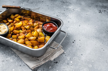 Patatas bravas traditional Spanish potatoes snack tapas in a steel tray. Gray background. Top view....