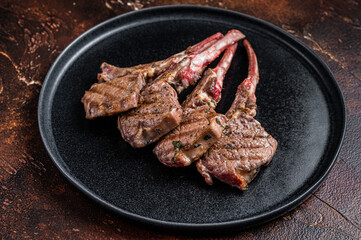 BBQ Grilled lamb chops steaks in a plate. Dark background. Top view