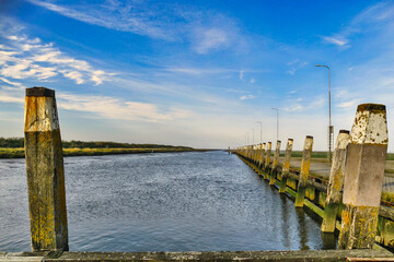 Row of old, weathered  mooring posts along a deserted harbour. Lichen- and alga-covered old mooring posts along the small tidal harbour of Noordpolderzijl on de Wadden Sea in the Netherlands