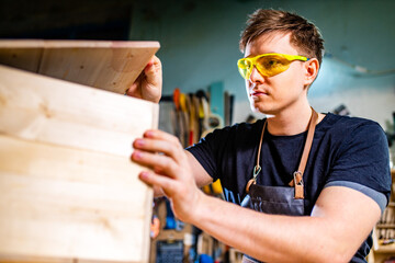 Young carpenter sawing board with circular saw
