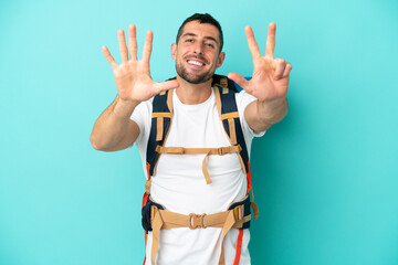 Fototapeta premium Young mountaineer caucasian man with a big backpack isolated on blue background counting eight with fingers