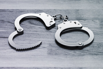 Police metal handcuffs on wooden background. Criminal justice and suspect arrest concept: steel handcuffs on floor, 3D render. - 466798846