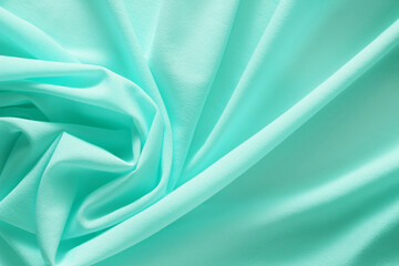 turquoise material flows in soft folds background