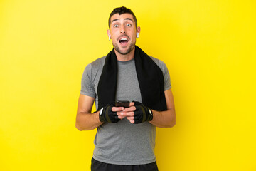Young sport caucasian man isolated on yellow background surprised and sending a message
