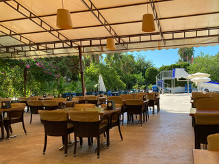 Cafe with umbrellas on background of sea and palm trees, the island of Santorini, Greece