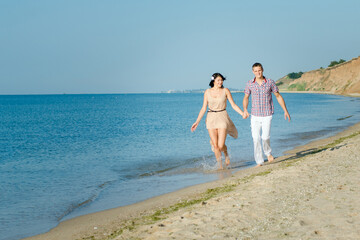 a guy and a girl walk along the seashore