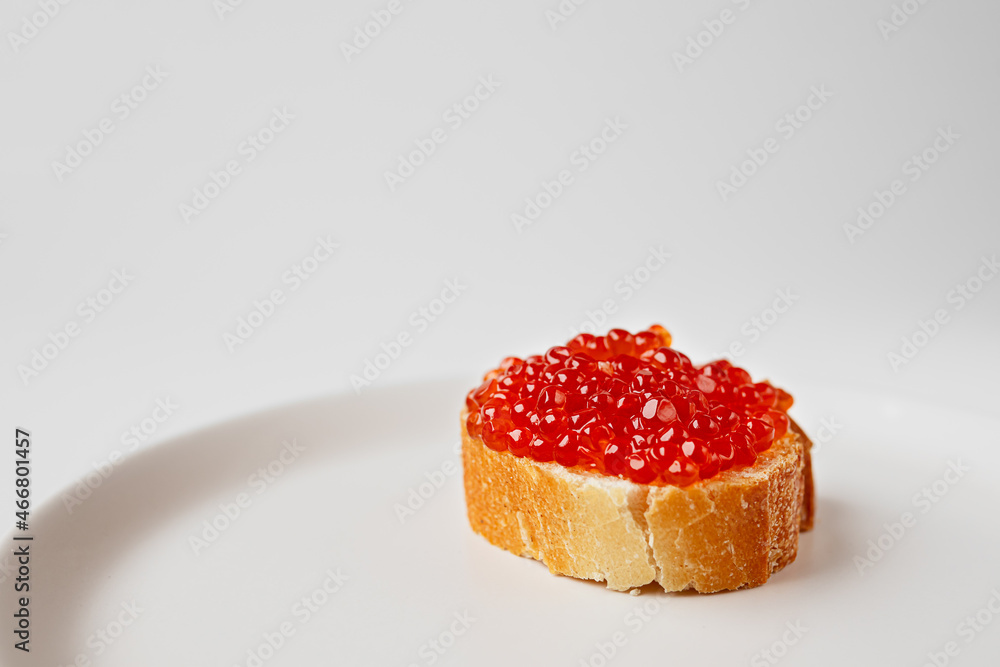 Wall mural a red caviar sandwich on a plate on a white table