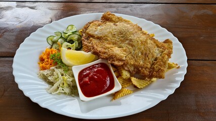 Large piece of grilled meat with homemade potatoes and fresh salad on a white plate