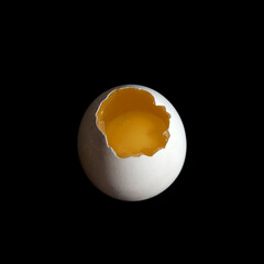 A white raw egg in a shell broken from above the yolk is visible on a black background