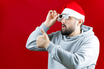 a man in a red Santa Claus hat adjusts his glasses for watching movies and gives a thumbs up