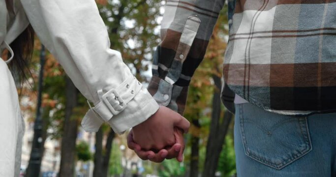 Soft focus on human hands. Concept of love, tenderness, affection, togetherness. Unrecognizable couple in love holding hands while walking together during romantic date outside. Close-up