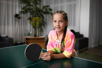 Portrait of girl playing ping-pong and looking at camera