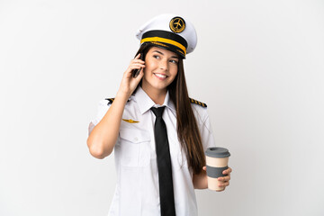 Brazilian girl Airplane pilot over isolated white background holding coffee to take away and a mobile