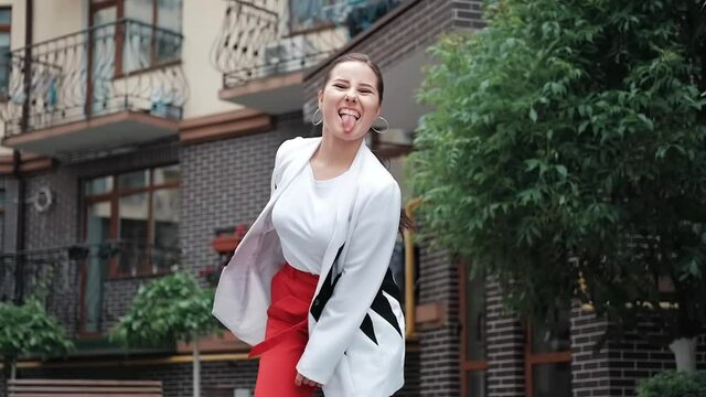 confident brunette woman in red pants and white blouse and jacket walking in the street. slow motion.