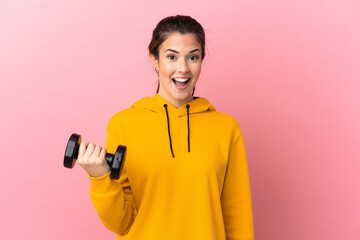 Young sport girl making weightlifting over isolated pink background with surprise facial expression
