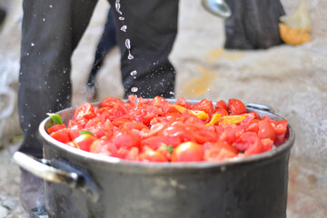 man cooking tomato soup on camp fire. wild nature resting. cutting tomatoes. Chopped juicy canned tomatoes in big bowl, tomato soup