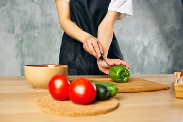 Cook woman on the kitchen cutting vegetables