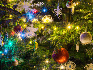 Sparkling lights on the Christmas tree. Hanging baubles and candies