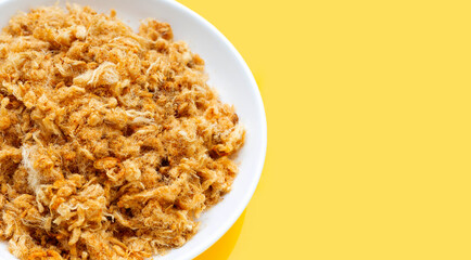 Dried shredded pork in white plate on yellow background.