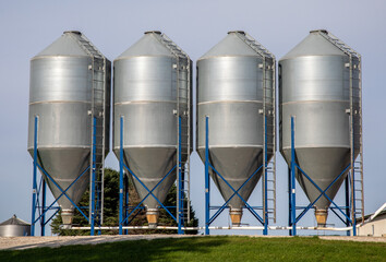four feed bins side-by-side on a cattle farm