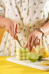Female hands about to cut a bright green bubble candle surrounded by lemon and lime halves, fresh thyme