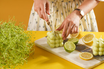 Female hands about to cut a bright green bubble candle surrounded by lemon and lime halves, fresh thyme