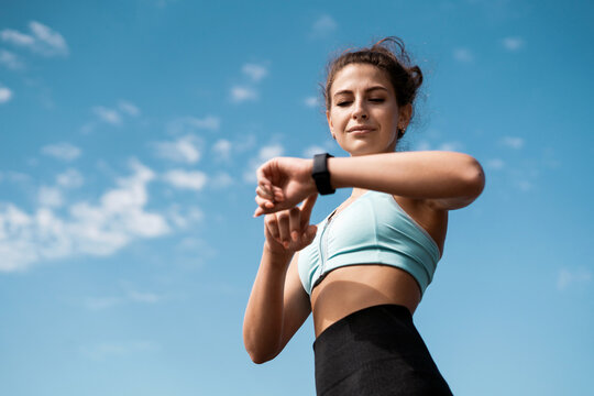 The athlete watches cardio, fitness in the city. A woman looks at sports and counts calories during training.  Exercise coach on the street, healthy lifestyle.