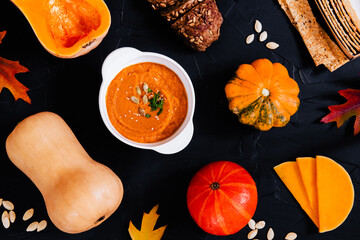 Flat lay of pumpkin foods during the autumn season. Pumpkin purée soup, bread and vegetables.