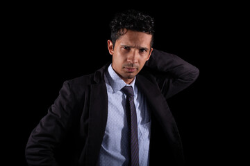 Young latin businessman posing with front view, isolated on black background. Attractive man wearing business suit.