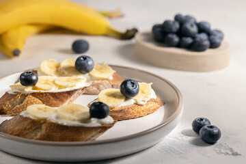 Healthy breakfast toasts with bananas and blueberry on toasted bread, close up