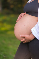 Silhouette of a pregnant woman in the 9th month of pregnancy, pregnant session in a forest
