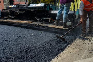 Work of street repair. Hispanic workers doing heavy duty of machinery for asphalt street construction.